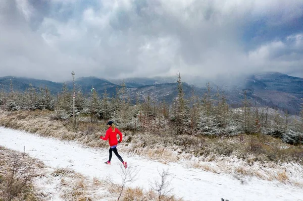 一个女赛跑选手在雪地里冬山小径上的无人驾驶图片. — 图库照片