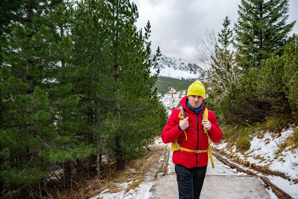 Гарний турист в червоній куртці, жовтий капелюх і рюкзак стоїть на гірській стежці . — стокове фото