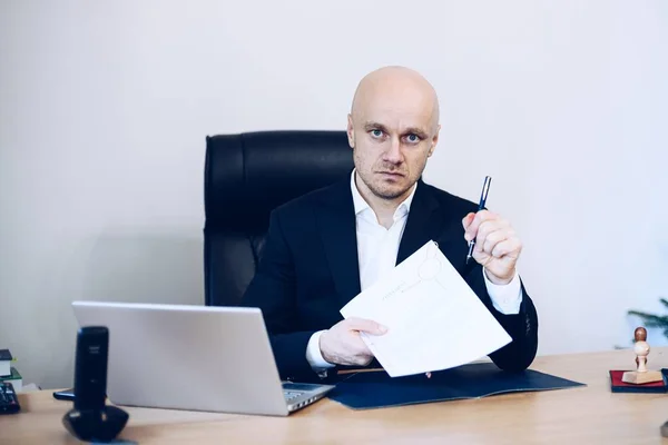 A handsome lawyer sitting at a wooden table giving a contract to be signed by the client — Stock Photo, Image