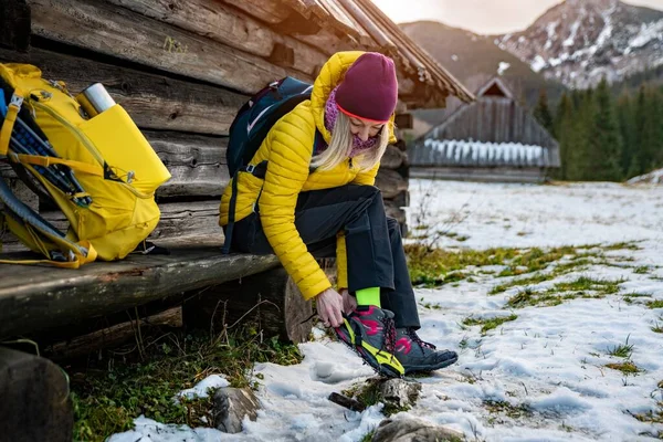 穿着黄色羽绒服的金发女登山者在到达登顶前在鞋子上贴上蜡笔. — 图库照片