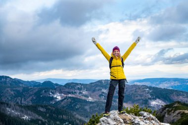 Üstte sarı ceketli başarılı bir yürüyüşçü kadın..