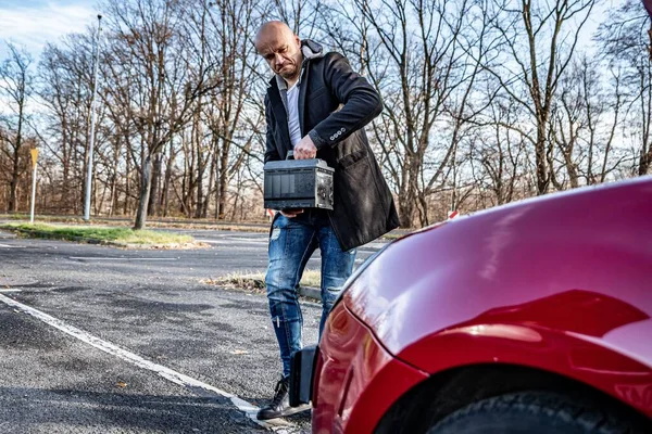 Irradiated man holding car battery. Broken car problem — Stockfoto
