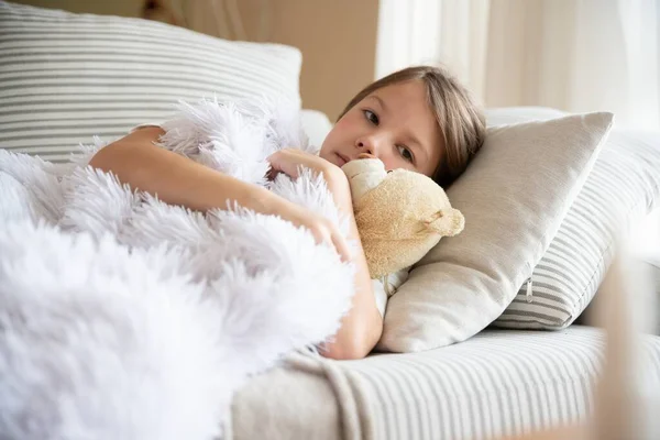 Güzel kız hasta, battaniyenin altında oyuncak ayıya sarılıyor.. — Stok fotoğraf