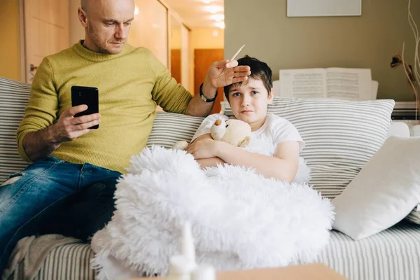 Un padre soltero mide la fiebre de sus hijos y llama a un médico para pedir consejo. — Foto de Stock