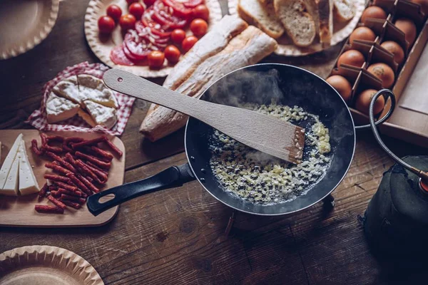 Preparing delicious tourist breakfast outdoors. Frying scrambled eggs in the mountains.