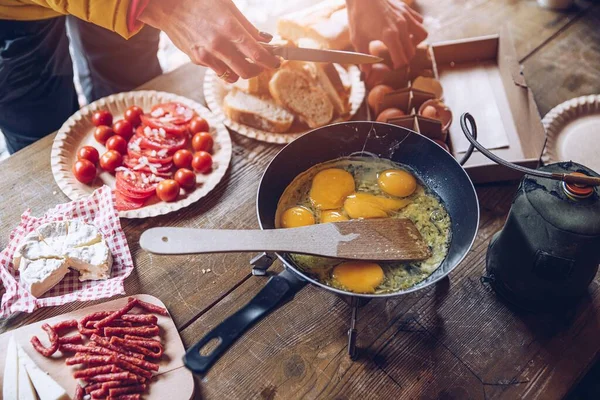 Mujer preparando delicioso desayuno turístico en el camping. Freír huevos revueltos al aire libre. —  Fotos de Stock
