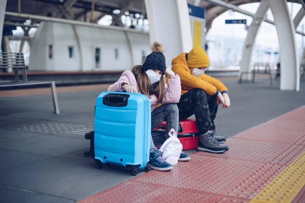 Traurige Kinder sitzen auf Taschen und wollen in den Winterurlaub. — Stockfoto