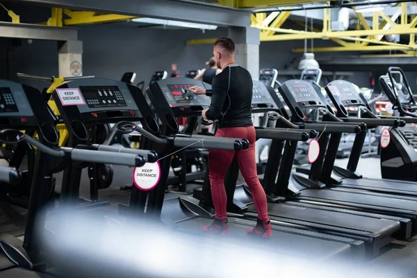 El hombre en el gimnasio empieza a correr en la cinta. —  Fotos de Stock