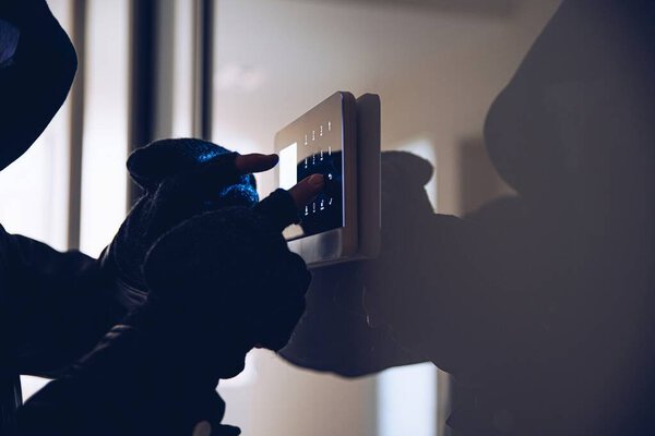 Руки вора, пытающегося обезвредить сигнализацию в доме.