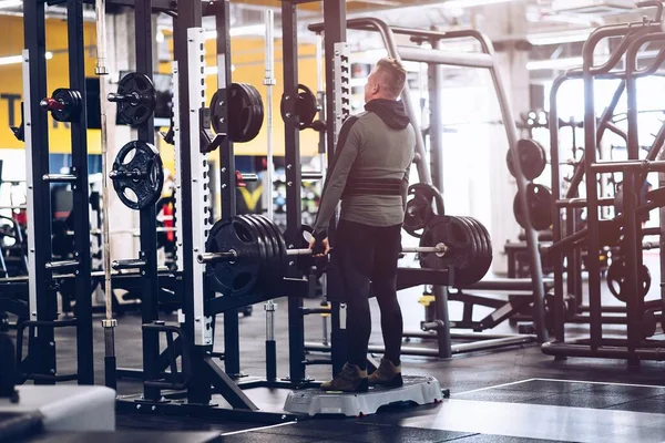 De man in de sportschool tilt gewichten op.. — Stockfoto