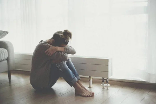Samotna młoda kobieta czuje się przygnębiona i zestresowana siedząc na podłodze z głową w rękach.. — Zdjęcie stockowe