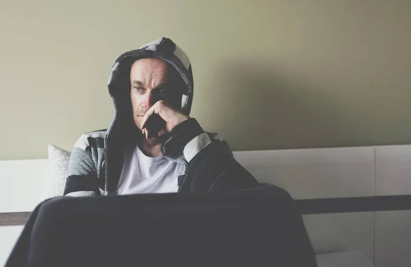 Sad pensive man sitting on the bed in the bedroom. — Stock Photo, Image