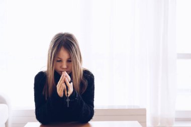 Oturma odasında elinde tespihle dua eden tatlı bir kız..