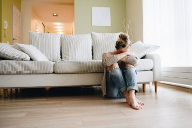 Depresyondaki genç kadın evde yerde oturuyor..