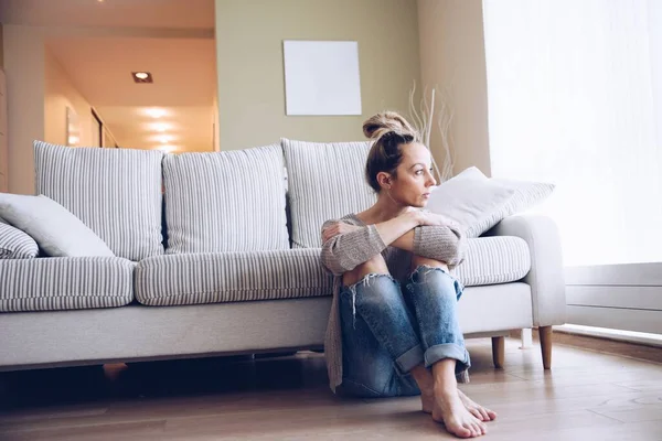 A lonely young woman feels depressed and stressed. She is sitting on the floor. — Stock Photo, Image