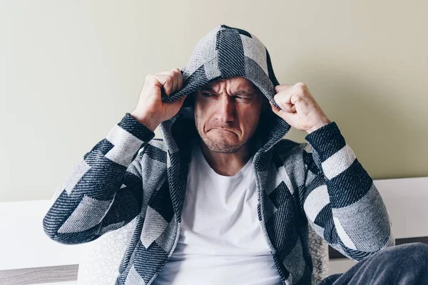 An angry, furious, depressed man is holding the hood. — Stock Photo, Image