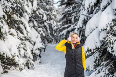 Gülümseyen sarışın bir yürüyüşçü güzel bir kış gününde bir dağ yolunda duruyor..