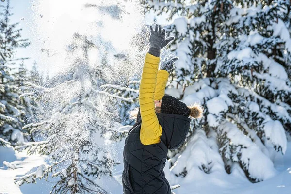 Mujer joven lanzando nieve en el aire en el soleado día de invierno. —  Fotos de Stock