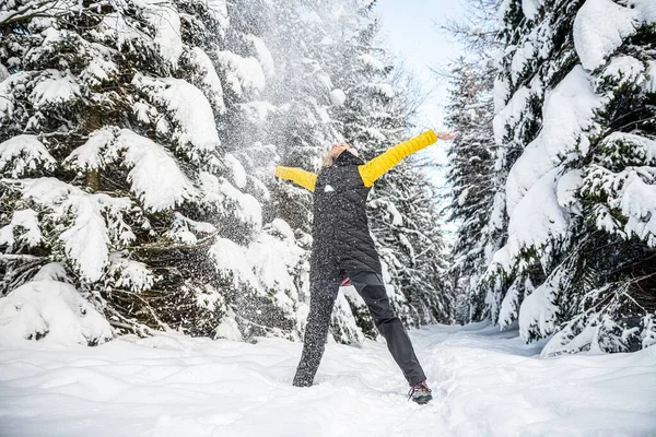 Жінка з піднятими руками кидає сніг у чудовий зимовий день . — стокове фото