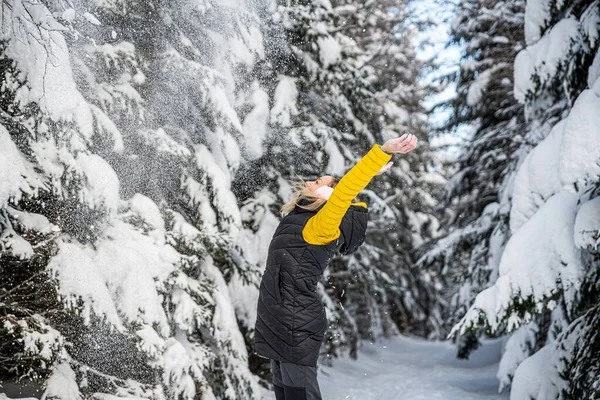 Donna felice sta gettando neve in una bella giornata invernale. — Foto Stock