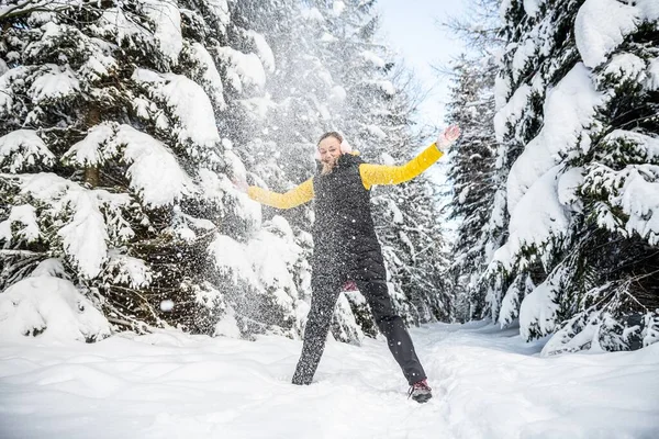 Diversión en la nieve. Hermosa mujer en orejeras está lanzando nieve en un maravilloso día de invierno. —  Fotos de Stock