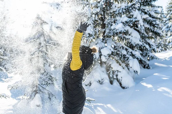 Femme heureuse jetant de la neige dans les airs à la journée ensoleillée d'hiver. — Photo