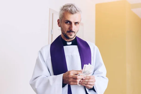Sacerdote católico polaco sosteniendo y contando dinero durante visita pastoral — Foto de Stock