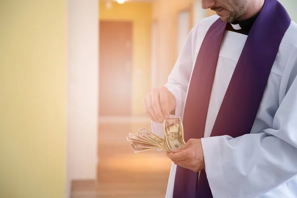 Catholic cleric priest counting american money dollar.