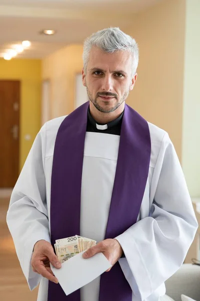 牧歌的な訪問中にお金を保持し、カウントポーランドのカトリック司祭 — ストック写真