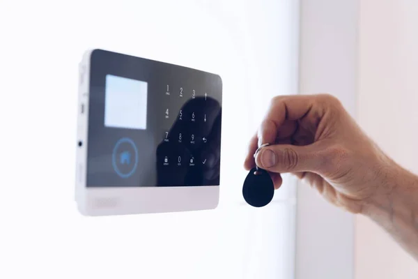 La mano con el mando a distancia desarma el sistema de seguridad. — Foto de Stock