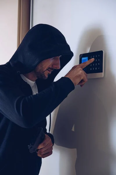 Un ladrón irrumpe en una casa. Está tratando de desarmar el sistema de alarma.. — Foto de Stock