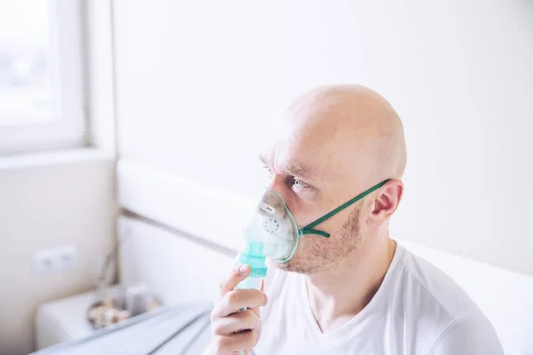 Coronavirus sick man breathing with oxygen mask. Patient in hospital.