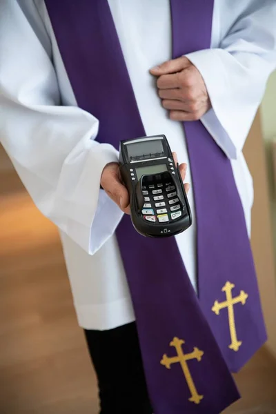 Le prêtre tient le lecteur de carte pendant la visite pastorale. — Photo