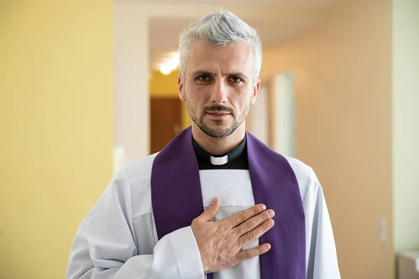 Sacerdote clérigo orando com a mão no coração — Fotografia de Stock