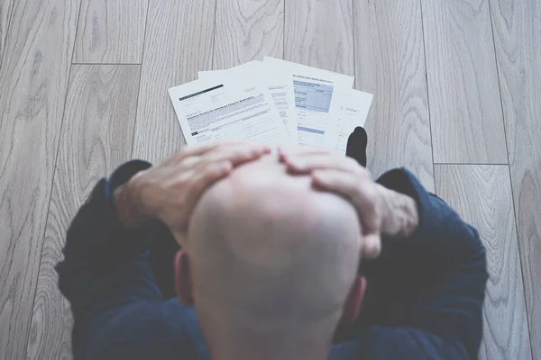 Desperate man sits on the floor. There are bankruptcy documents on the floor. — Stock Photo, Image