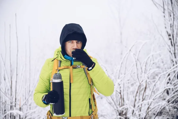 年轻人冬天在山上旅游，喝着热水瓶里的热饮料. — 图库照片