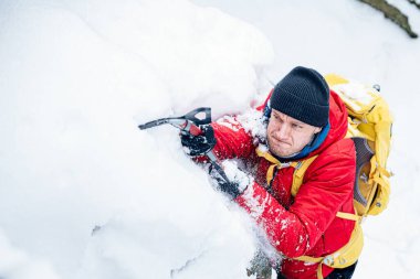 Buz baltası ile yakışıklı dağcı tırmanırken efor sarf ediyor..