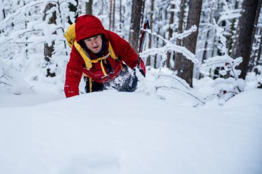 Kırmızı ceketli ve sarı çantalı bir dağcı buz baltasıyla tırmanıyor..