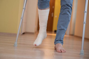 Koltuk değnekli bir adam. Kırık bacaklı genç bir adam.