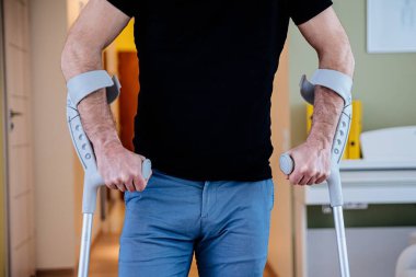 Koltuk değnekli bir adamın orta kısmını kapat..