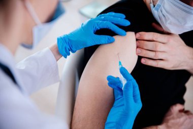 Covid-19 or coronavirus vaccine.Doctor injecting vaccination in arm of man patien.