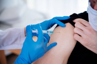 Man receiving an injection in his arm. Vaccinating the patient.