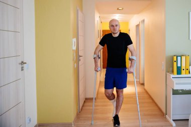 Koltuk değnekli ve bacağı kırık bir sporcu. Yaralanma, rehabilitasyon.