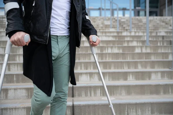 Close up on male legs on crutches on stairs. — Stock Photo, Image