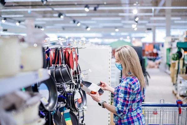 Kobieta wybierająca patelnię w supermarkecie. Zakupy podczas blokady. — Zdjęcie stockowe