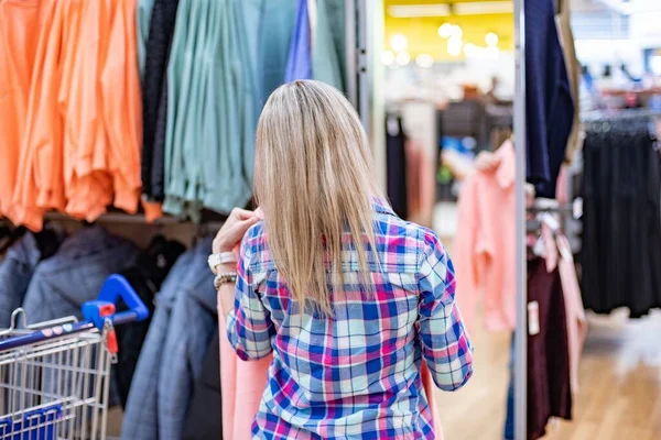 Mujer comprando en el supermercado. Ella eligió ropa en el supermercado. —  Fotos de Stock