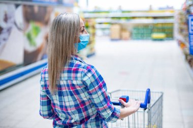 Marketten alışveriş yapan koruyucu maskeli bir kadın..