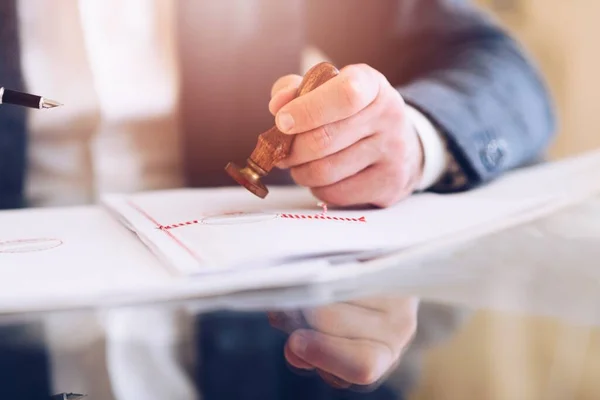 Der Notar stempelt ein Notarsiegel auf das Vertragspapier oder eine Urkunde im Büro. — Stockfoto