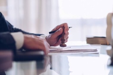 Adamın elinde bir kalem ve noter damgası var..