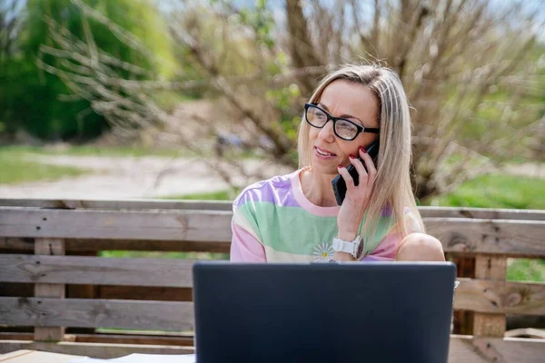 Freelance blonde woman with glasses works outdoors. Office outside. — Stock Photo, Image